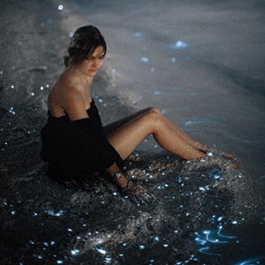 woman sitting on the shore of a bioluminescent bay