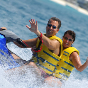 close-up of a couple who are wearing life vests and riding a waverunner on the ocean