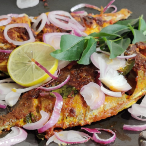 fresh fried fish that is garnished with lemon, red onions and leafy green herbs