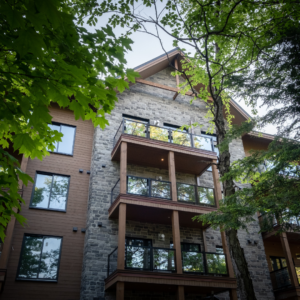 A close up of the facade of a timber and stone lodge set behind green trees 