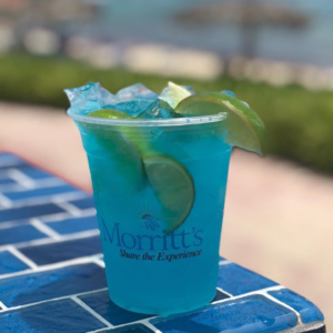 A bright blue cocktail garnished with slices of lime