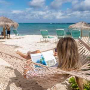 woman reading a book in a hammock on the beach