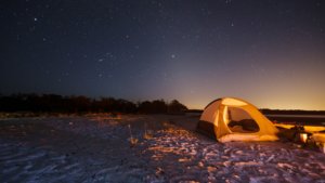 yellow tent pitched on a beach under the stars